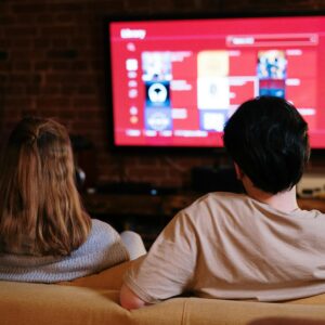 A couple enjoys streaming shows on a large TV in a cozy, brick-walled living room.